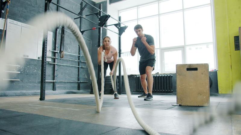 Duas pessoas treinando com cordas navais em um espaço de treino funcional