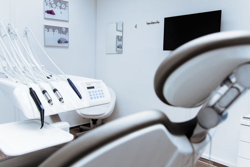 Consultório odontológico claro, com cadeira, refletor e equipamentos brancos